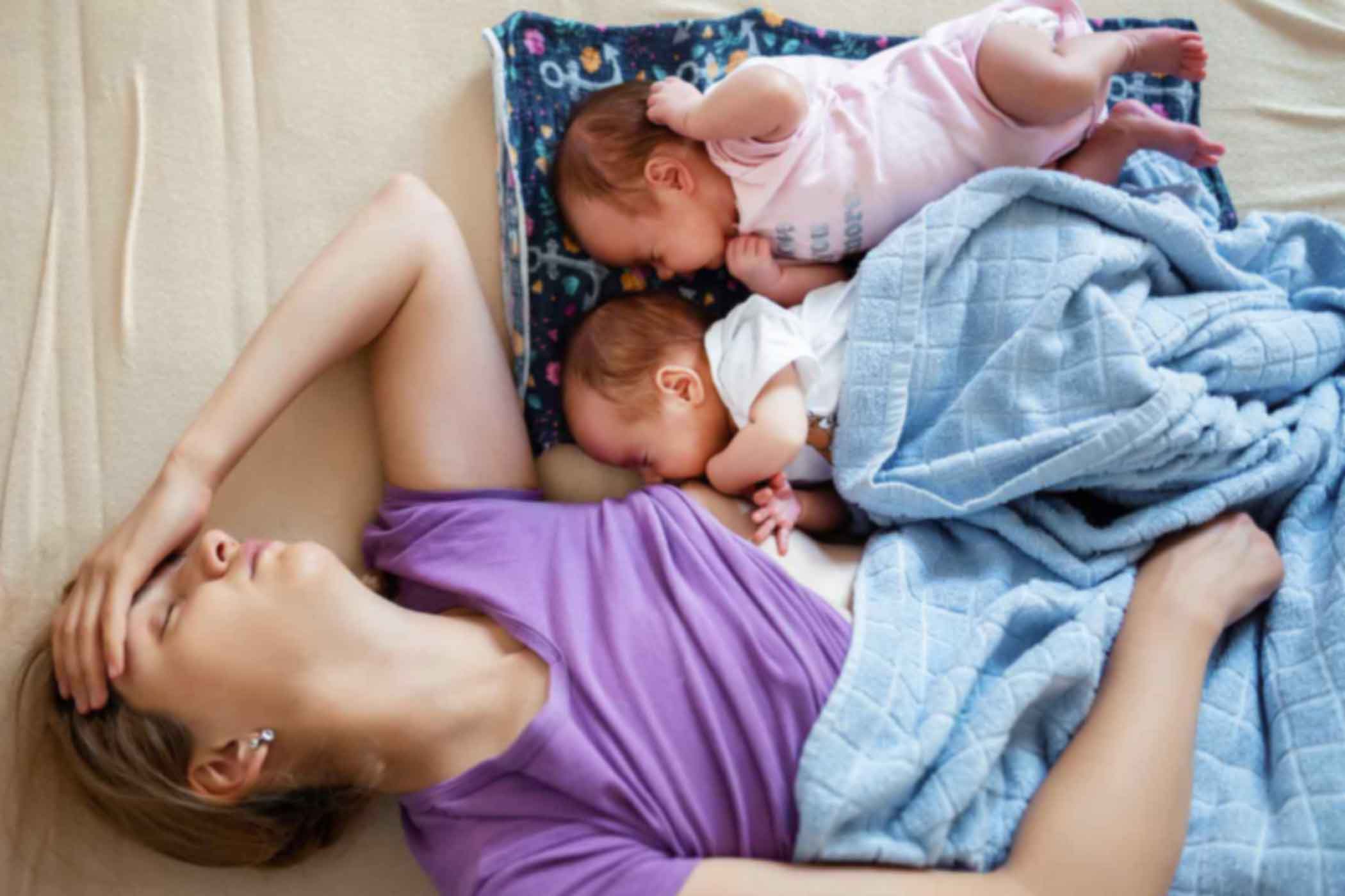 Beyond-the-Basics-Managing-Common-Breastfeeding-Challenges Stressed mom with twin babies sleeping by her side