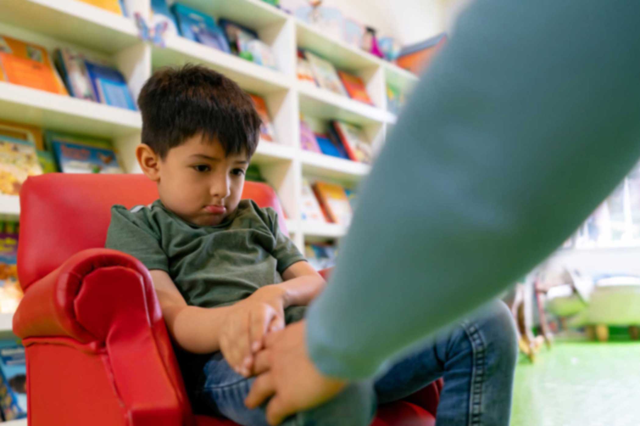 upset boy being reprimanded by an adult in school setting