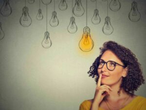 Woman thinking and looking at light bulbs drawings on wall