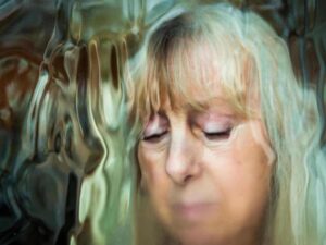 blurry image of a sad elder woman with her eyes closed