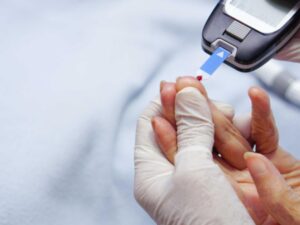 hand with glove measuring blood sugar through glucometer