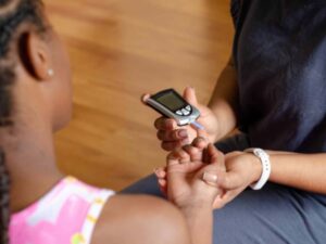 Nurse giving a finger stick test to a diabetic girl