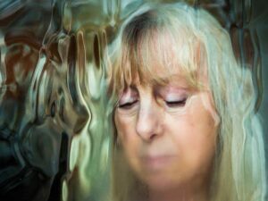 elder woman looking through a raining window